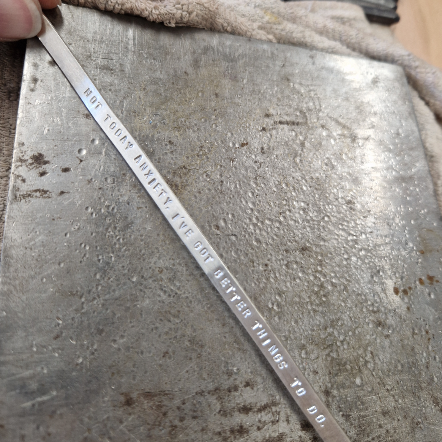 Metal strip with stamped text on a textured surface