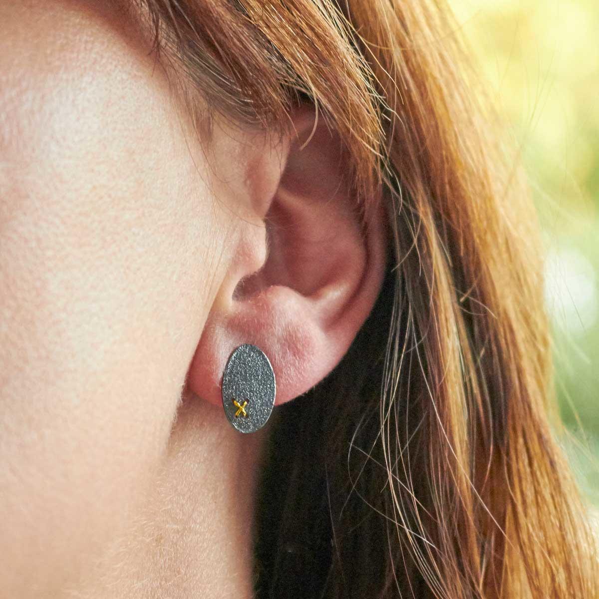 Oxidised (Blackened) Silver, Oval Studs with Tiny Gold Cross Stitch by Sara Bukumunhe. Image property of THE JEWELLERY MAKERS.-2