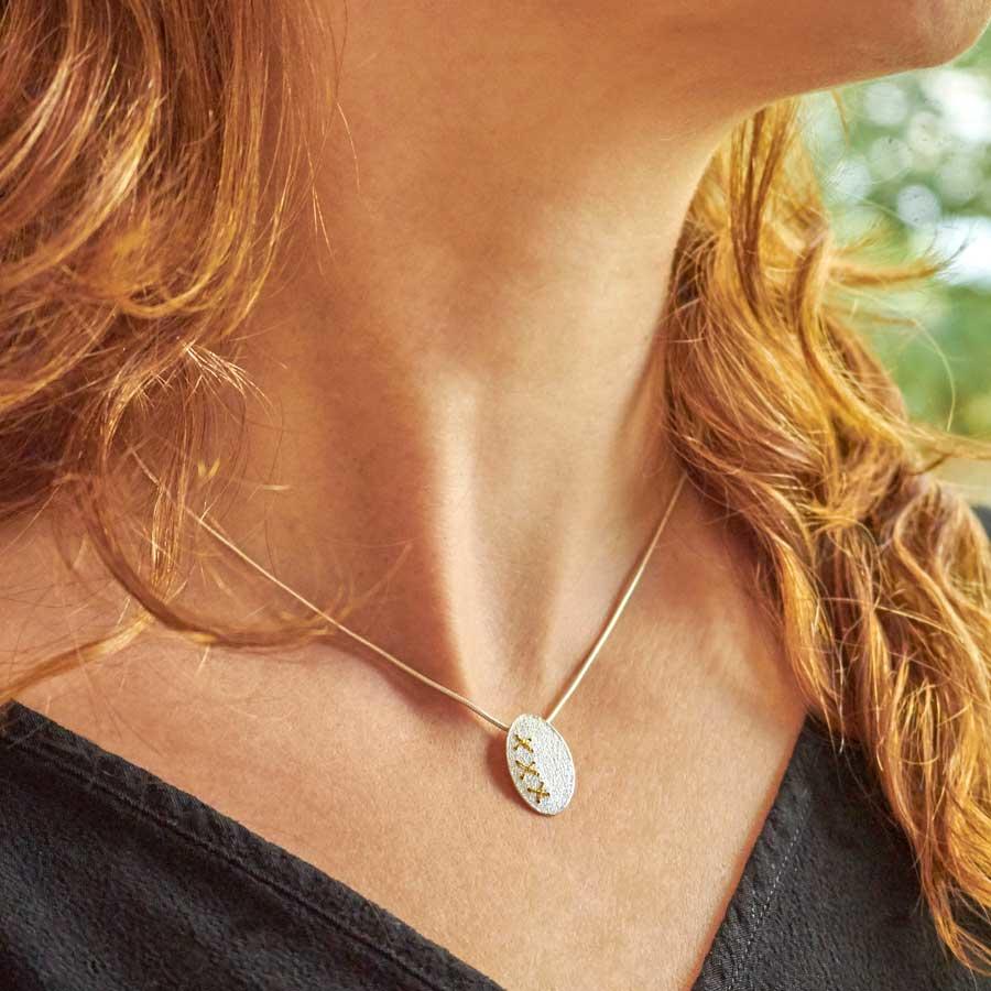 Silver Oval Cross Stitch Necklace with Gold thread by Sara Bukumunhe. Image property of THE JEWELLERY MAKERS-0
