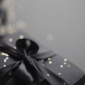 A silky black ribbon on a black gift box sprinkled with gold stars
