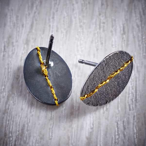 Oxidised (Blackened) Silver, Oval studs, sewn with Gold thread by Sara Bukumunhe. Image property of THE JEWELLERY MAKERS.-1