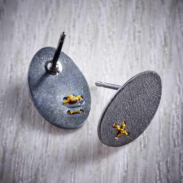 Oxidised (Blackened) Silver, Oval Studs with Tiny Gold Cross Stitch by Sara Bukumunhe. Image property of THE JEWELLERY MAKERS.-1