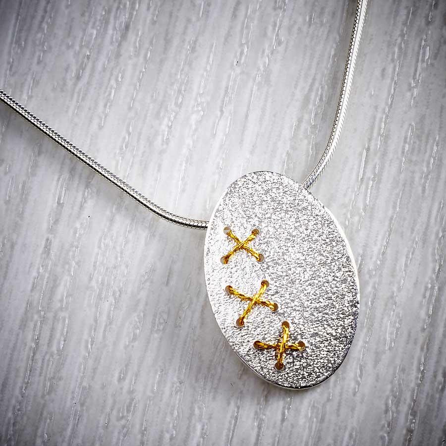 Silver Oval Cross Stitch Necklace with Gold thread by Sara Bukumunhe. Image property of THE JEWELLERY MAKERS-1