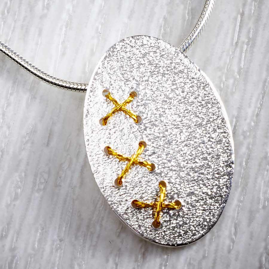 Silver Oval Cross Stitch Necklace with Gold thread by Sara Bukumunhe. Image property of THE JEWELLERY MAKERS-2
